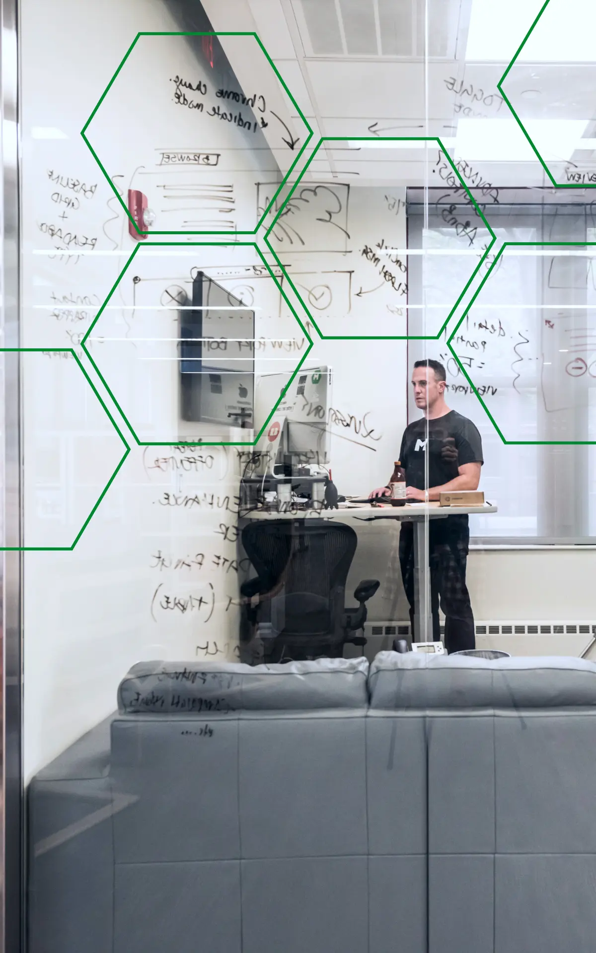 A MojoTech engineer working at a standing desk in front of a whiteboard covered in diagrams.
