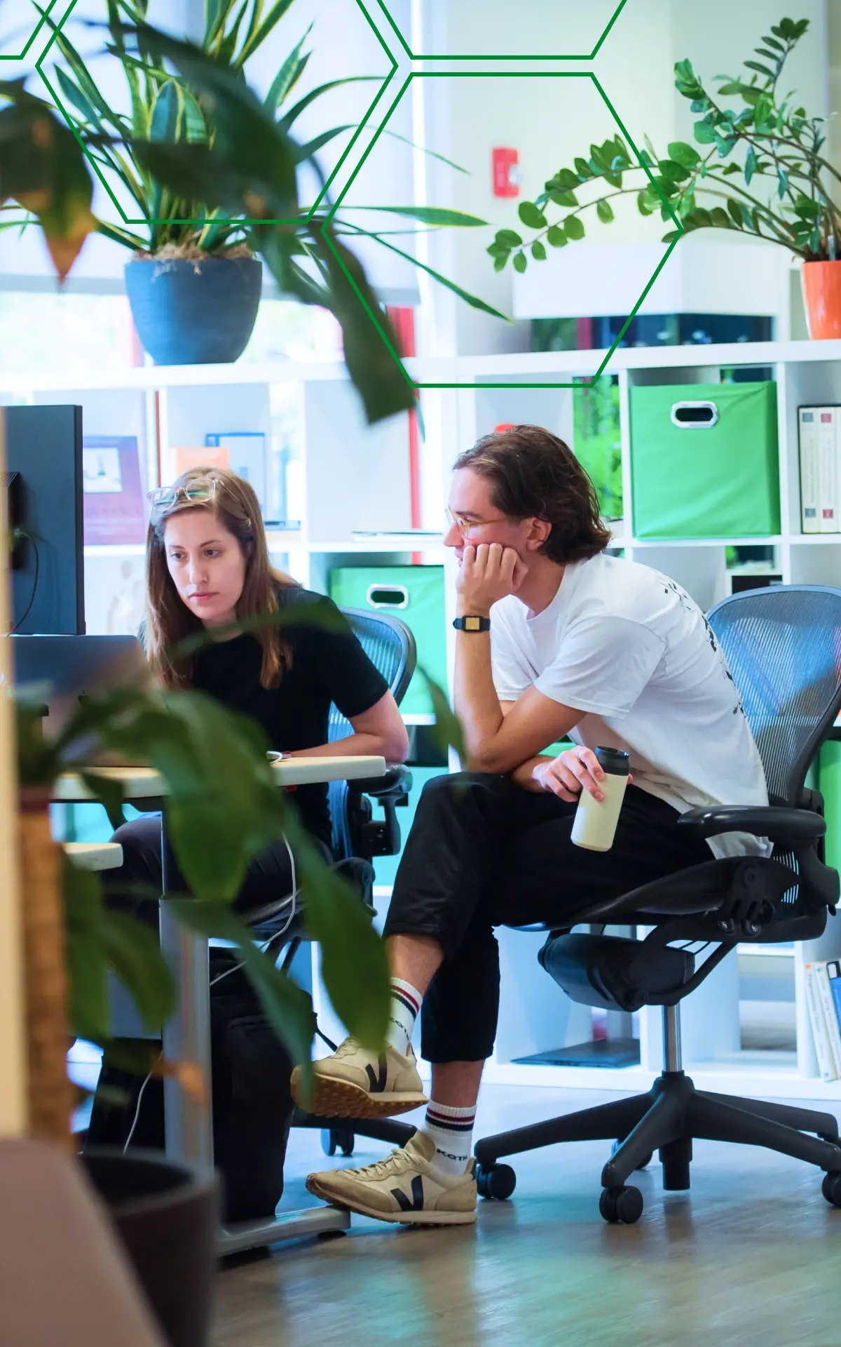 Two MojoTech product designers collaborating at their desks in the office.