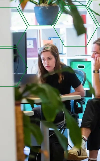 Two MojoTech product designers collaborating at their desks in the office.