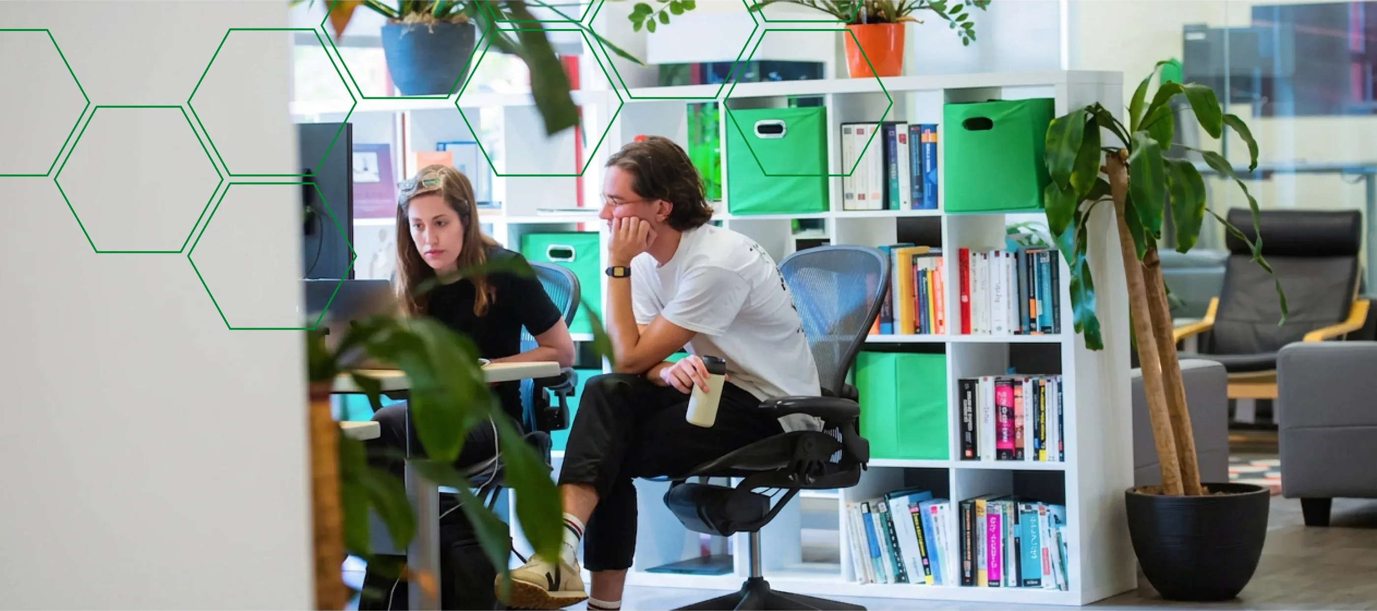Two MojoTech product designers collaborating at their desks in the office.