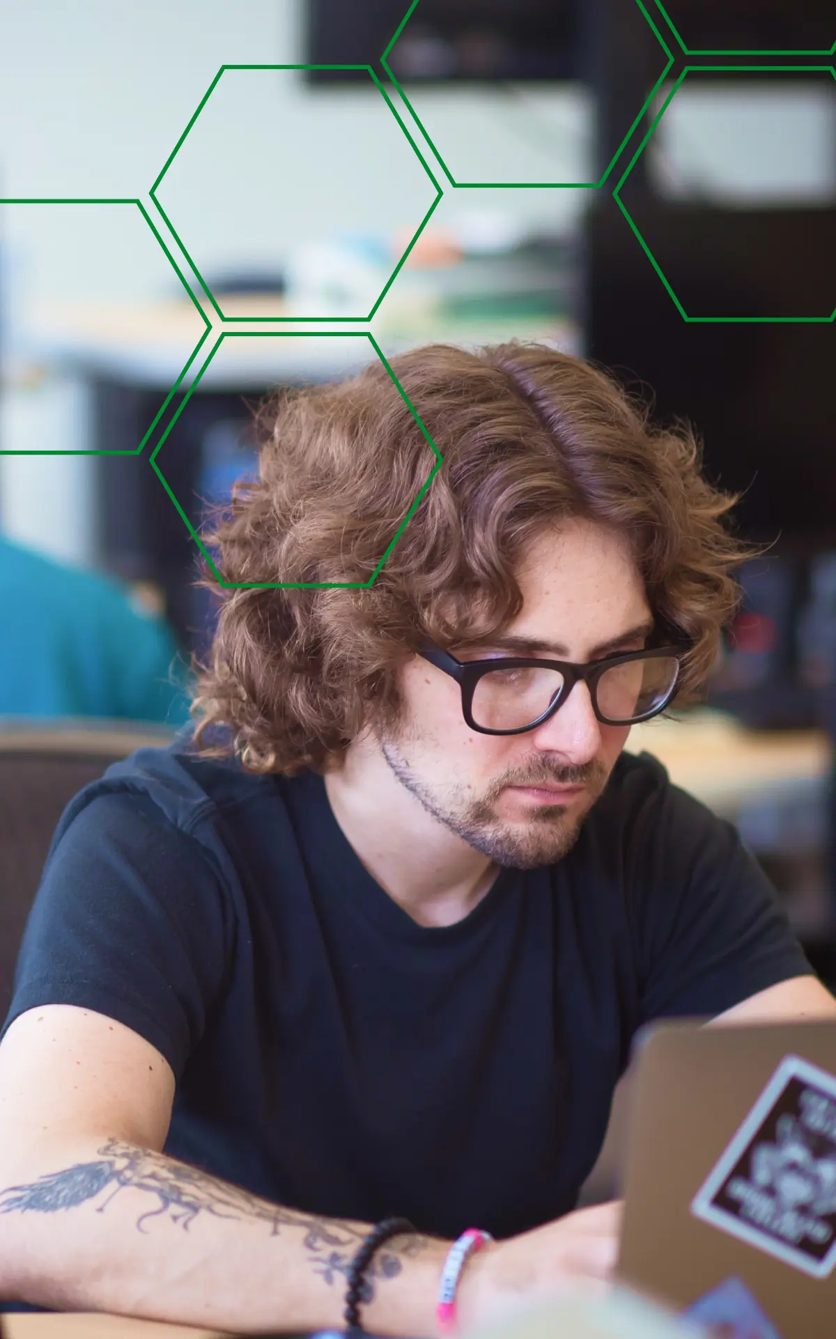 A MojoTech engineer working at a laptop with a colleague in the background.