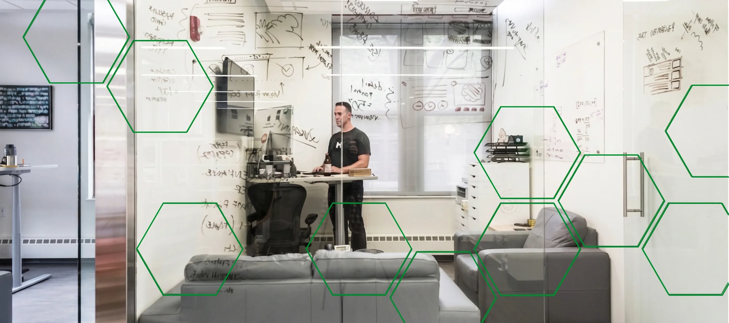 A MojoTech engineer working at a standing desk in front of a whiteboard covered in diagrams.