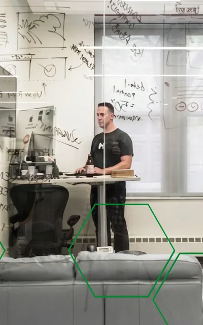 A MojoTech engineer working at a standing desk in front of a whiteboard covered in diagrams.